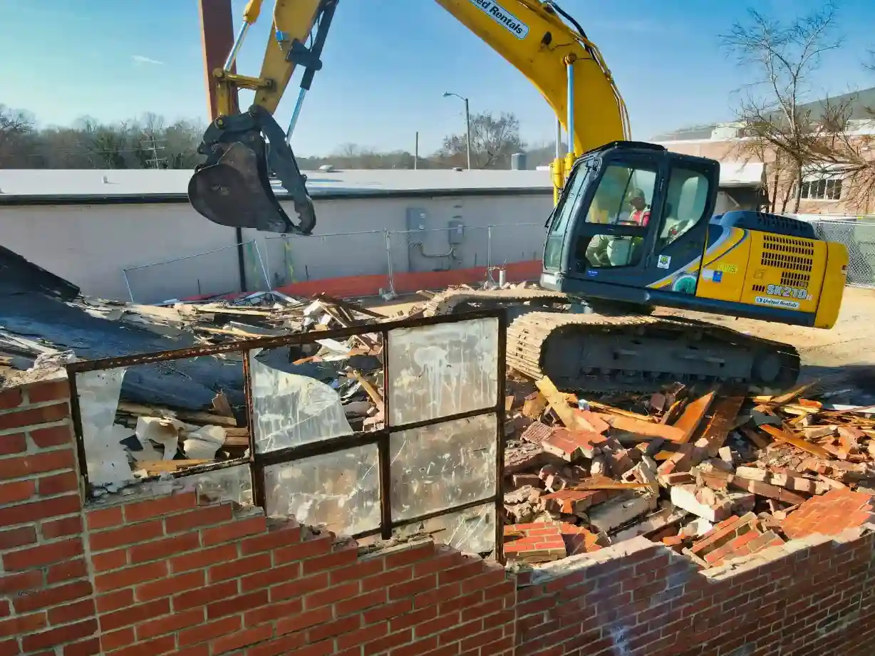 Excavator removing part of a residential structure during demolition work