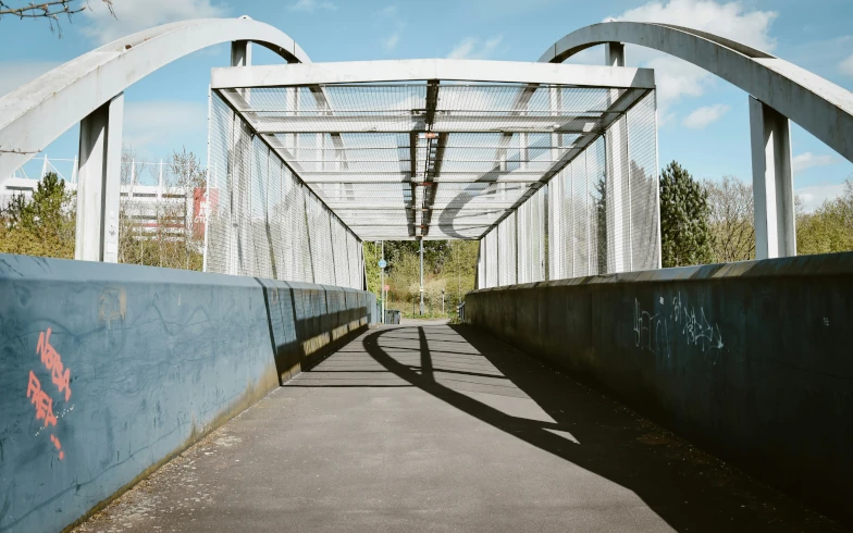 Covered pedestrian footbridge with steel arch supports