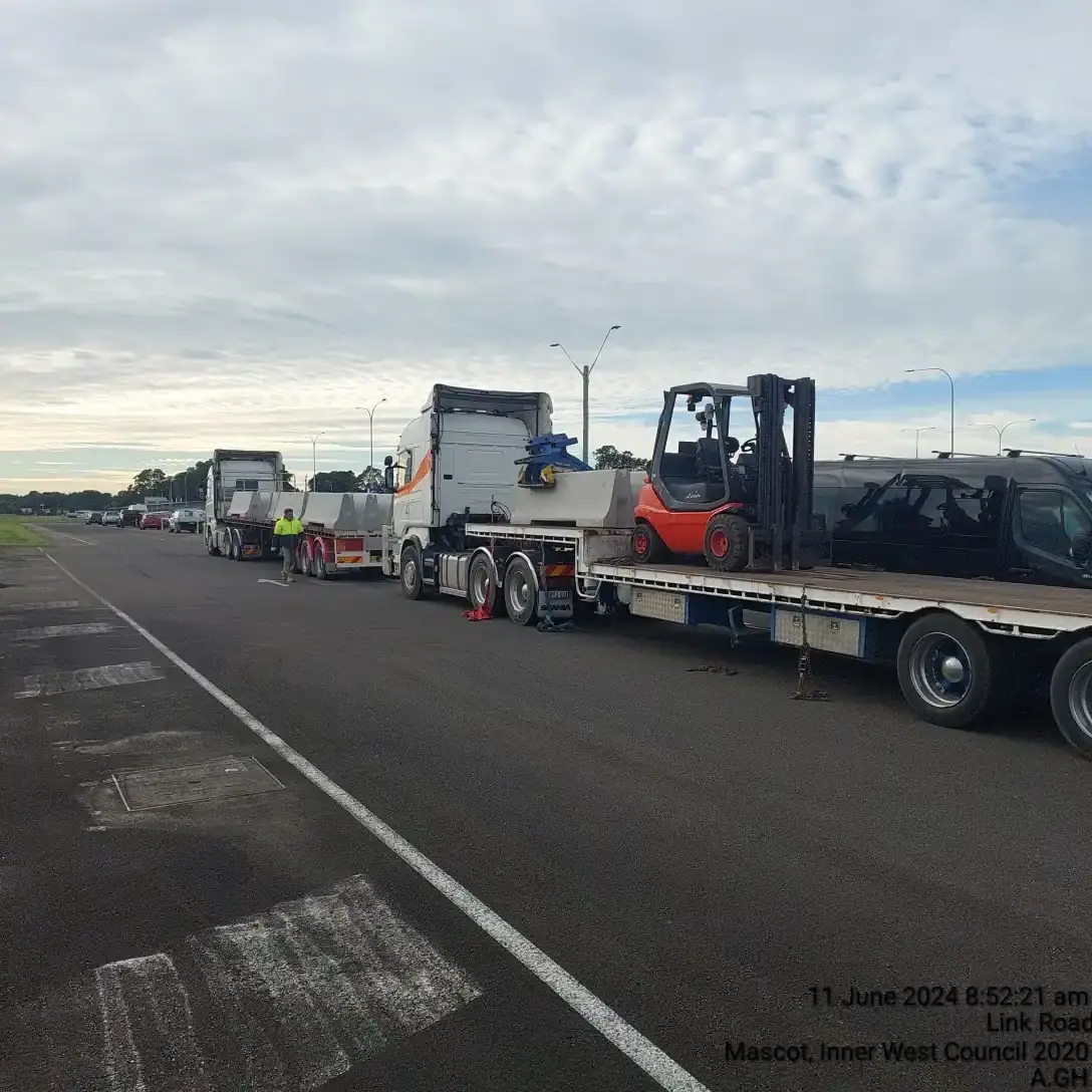 Delivery trucks, concrete barriers and forklift staged at Sydney Airport Blue Emu Car Park.