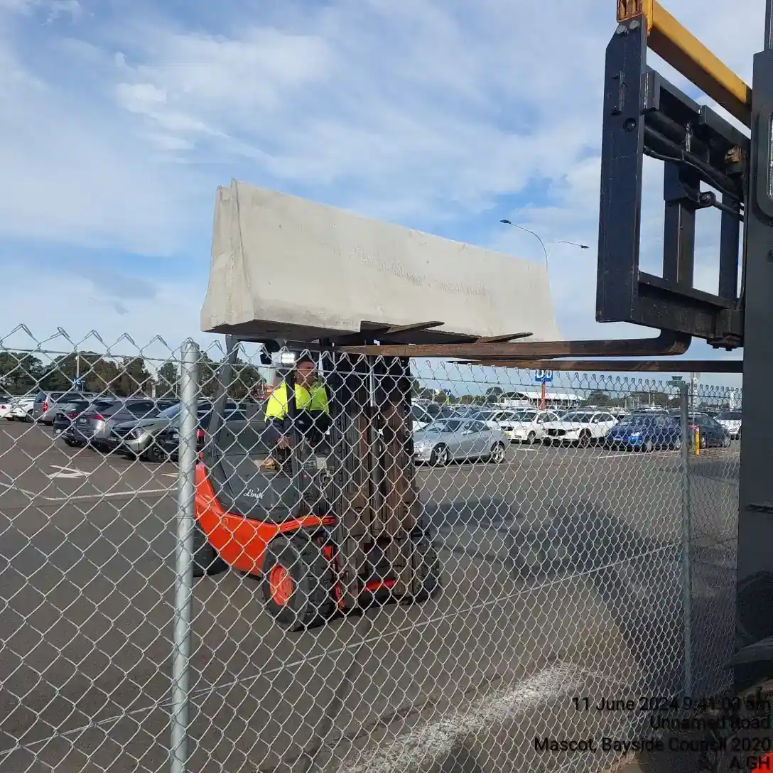Forklift positioning a concrete barrier at Sydney Airport Blue Emu Car Park.