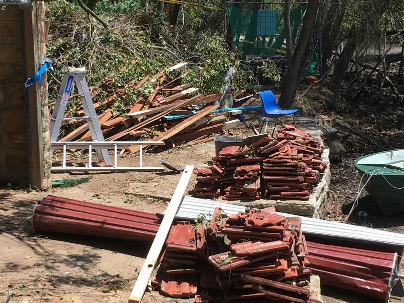 Removed roof tiles and timber beside the Grays Point boat shed