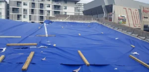 Heavy-duty blue tarpaulin covering the storm-damaged commercial roof in Ryde
