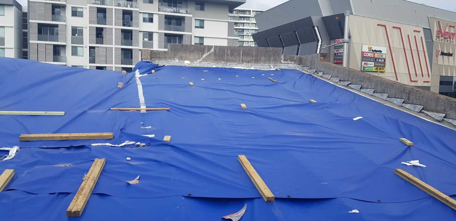 Heavy-duty blue tarpaulin covering the storm-damaged commercial roof in Ryde